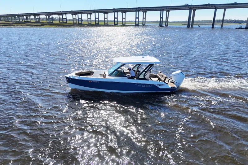 Slide: The Image of 2025 Monterey Elite 27 OB boat cruising on a sunny day near a bridge. - 15