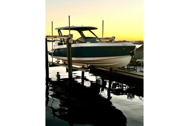 Slide: The Image of 2025 Monterey Elite 27 OB boat docked at sunset, reflecting on calm water. - 27