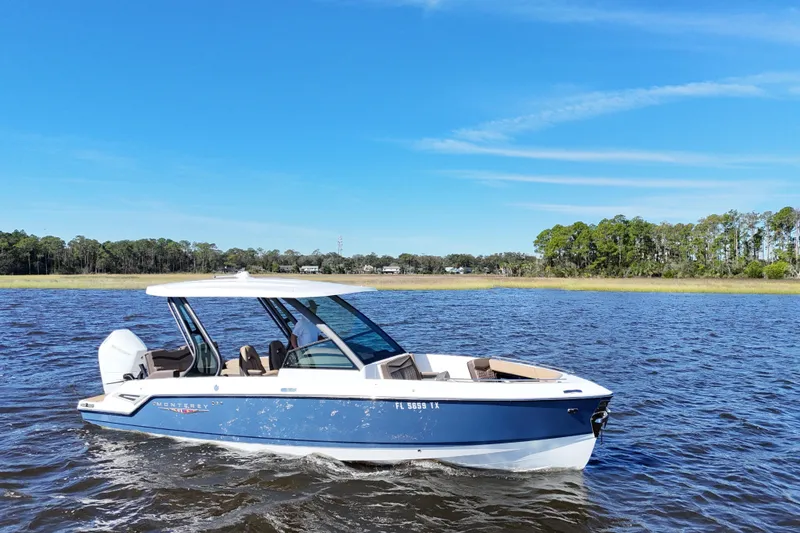 Slide: The Image of 2025 Monterey Elite 27 OB boat cruising on a scenic lake under a clear blue sky. - 3