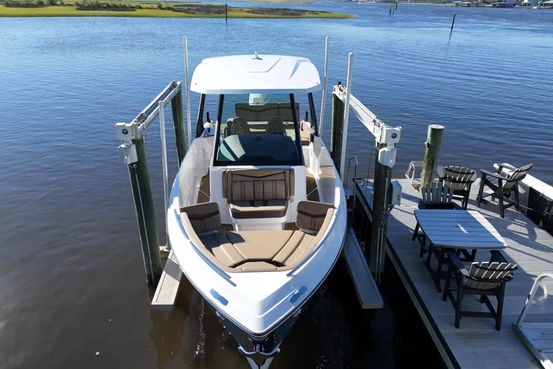 Slide: The Image of 2025 Monterey Elite 27 OB boat docked by a waterfront deck. - 30