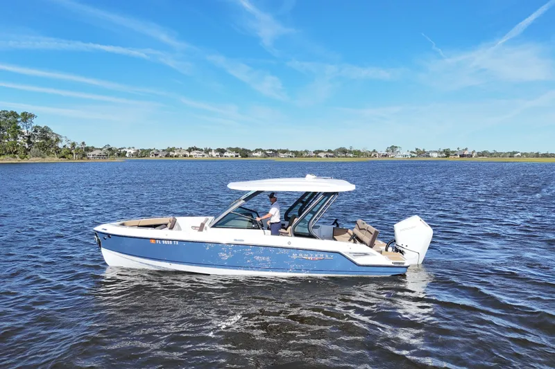 Slide: The Image of 2025 Monterey Elite 27 OB boat cruising on a calm lake under a clear blue sky. - 5