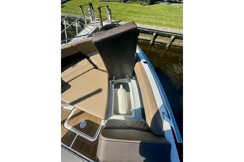 Slide: The Image of 2025 Monterey Elite 27 OB boat with open storage compartment, docked by grassy area. - 52