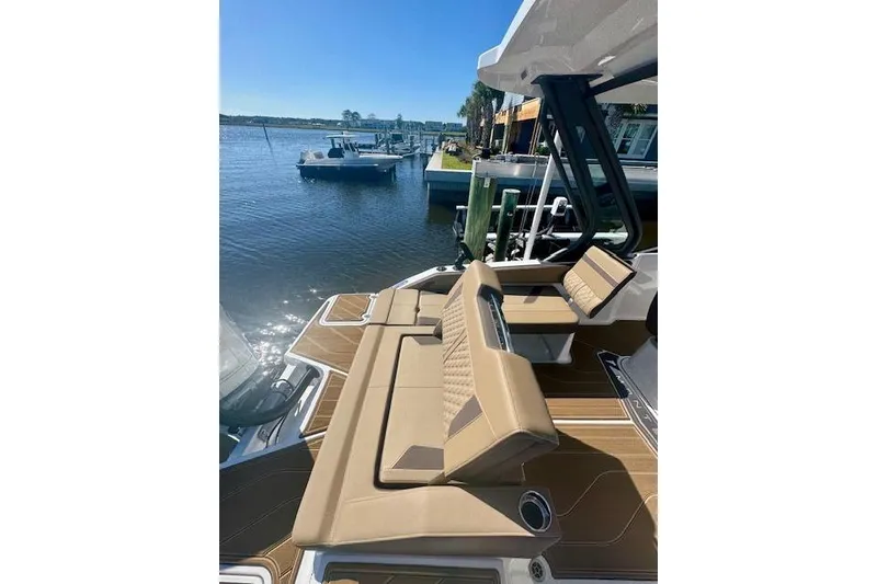 Slide: The Image of 2025 Monterey Elite 27 OB boat with tan seating, docked by a serene waterfront. - 53