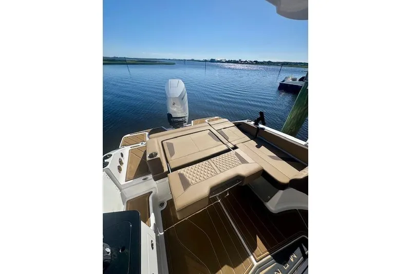 Slide: The Image of 2025 Monterey Elite 27 OB boat with tan seating, docked by calm waters. - 55
