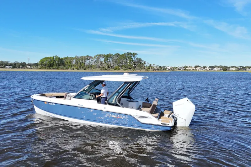 Slide: The Image of 2025 Monterey Elite 27 OB boat cruising on a calm lake under a clear blue sky. - 9