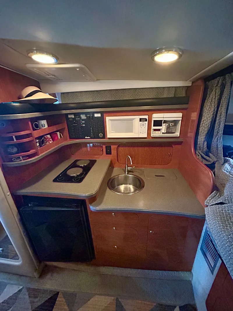 Slide: The Image of 2002 Rinker 342 Fiesta Vee boat kitchen with sink, stove, microwave, and storage shelves. - 12