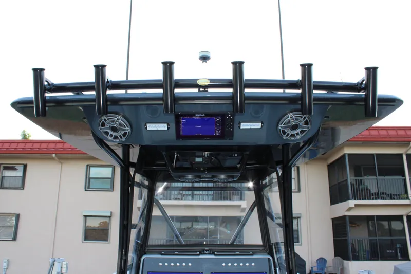 Slide: The Image of 2019 Conch 33 boat console with speakers and rod holders, docked near buildings. - 19