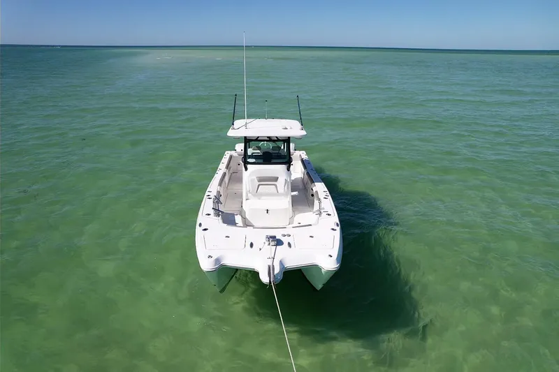 Slide: The Image of 2023 World Cat 325 CC boat anchored in clear turquoise water. - 11