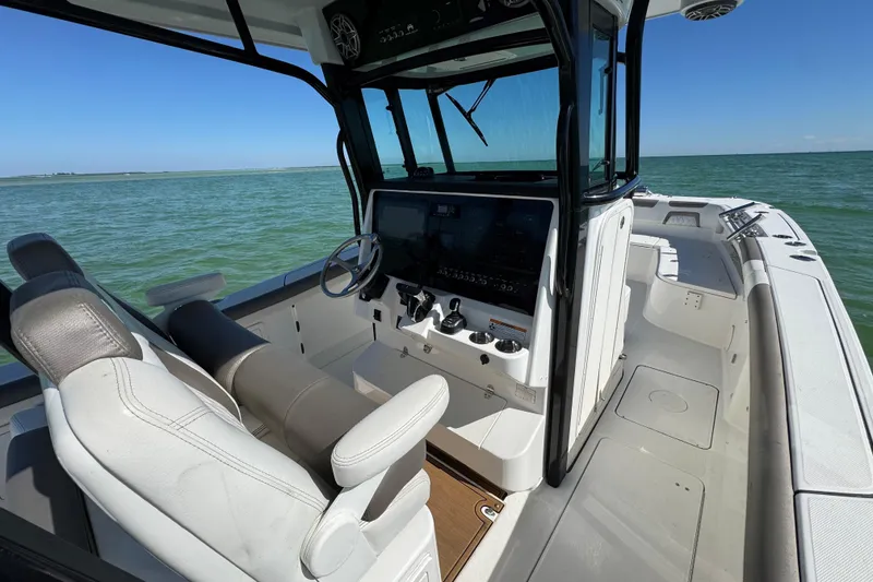 Slide: The Image of 2023 World Cat 325 CC boat interior with helm, steering wheel, and ocean view. - 26