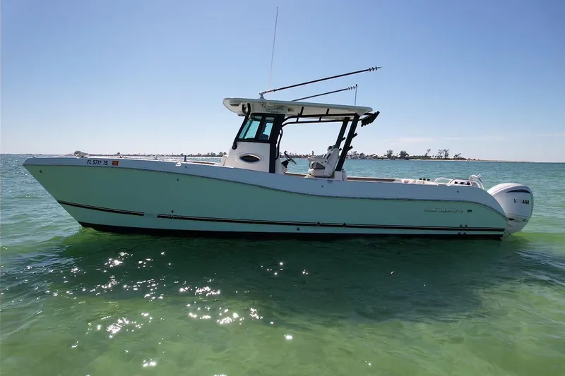 Slide: The Image of 2023 World Cat 325 CC boat on calm green water under clear blue sky. - 7