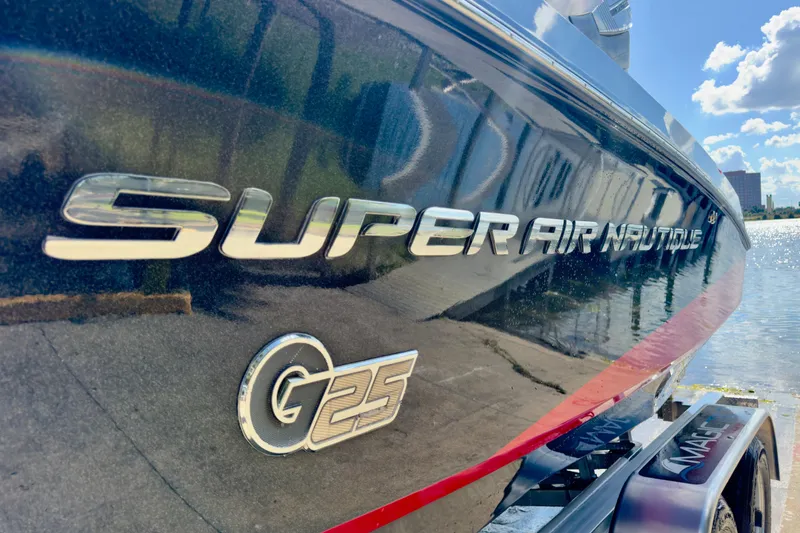 Slide: The Image of 2015 Nautique Super Air Nautique G25 Coastal Edition boat by the water. - 2
