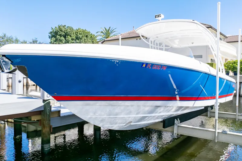 Slide: The Image of 2015 Intrepid 327 Cuddy boat in blue and white, docked on a lift. - 10