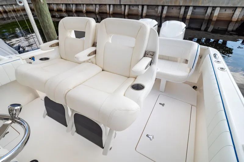 Slide: The Image of 2015 Intrepid 327 Cuddy boat interior with white cushioned seating and cup holders. - 2