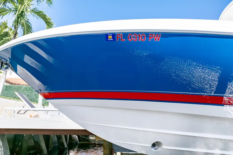 Slide: The Image of 2015 Intrepid 327 Cuddy boat with blue hull and red stripe, docked in sunny Florida. - 28