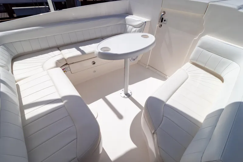 Slide: The Image of 2015 Intrepid 327 Cuddy boat interior with white seating and a small table. - 34