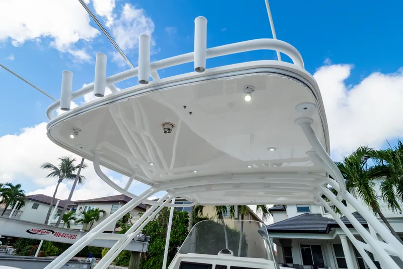 Slide: The Image of 2015 Intrepid 327 Cuddy boat with white canopy and rod holders against blue sky. - 44