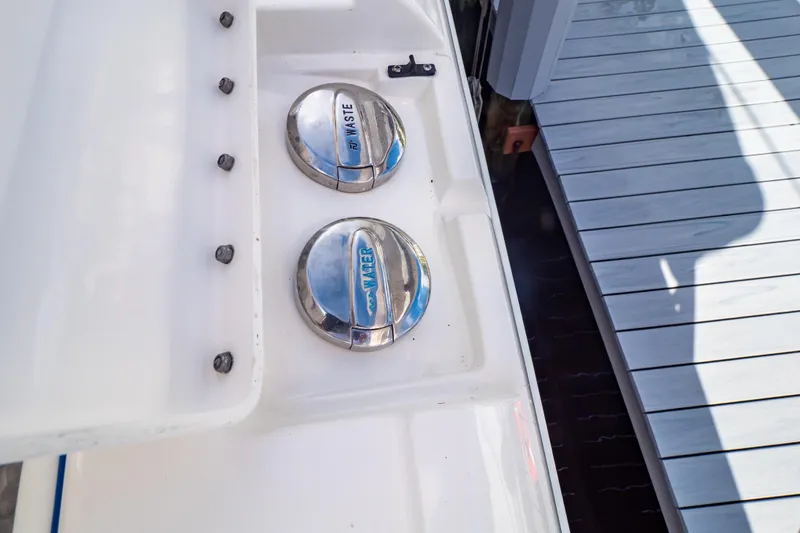 Slide: The Image of Fuel and water caps on a 2015 Intrepid 327 Cuddy boat near a dock. - 61