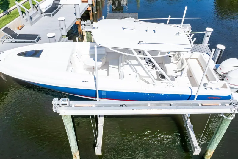 Slide: The Image of 2015 Intrepid 327 Cuddy boat docked on lift, blue and white design. - 62