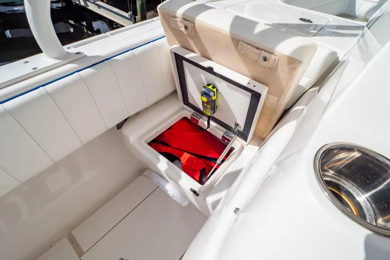 Slide: The Image of 2015 Intrepid 327 Cuddy boat storage compartment with safety equipment and red life jacket. - 69