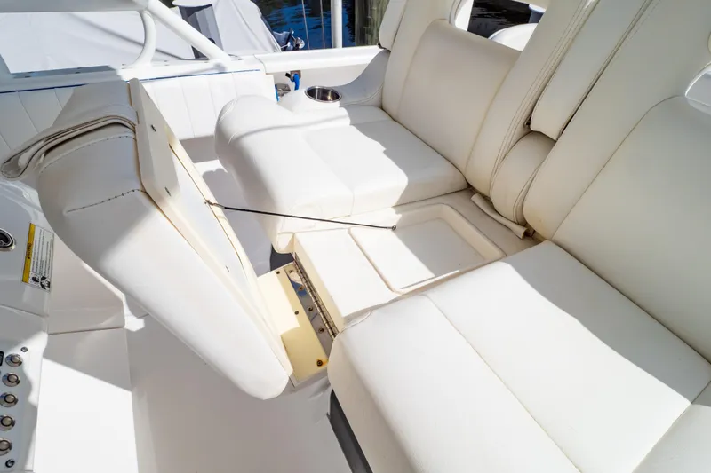 Slide: The Image of 2015 Intrepid 327 Cuddy boat interior with white cushioned seating and storage compartment. - 71