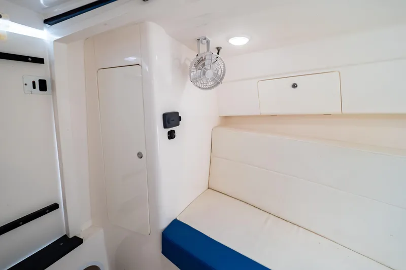 Slide: The Image of 2015 Intrepid 327 Cuddy interior with white seating and storage compartments. - 80