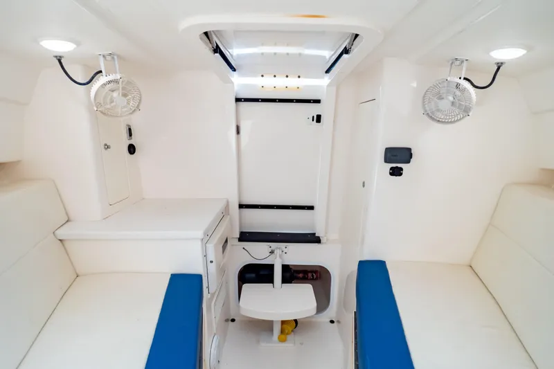 Slide: The Image of Interior of a 2015 Intrepid 327 Cuddy boat, featuring white seating and compact design. - 81