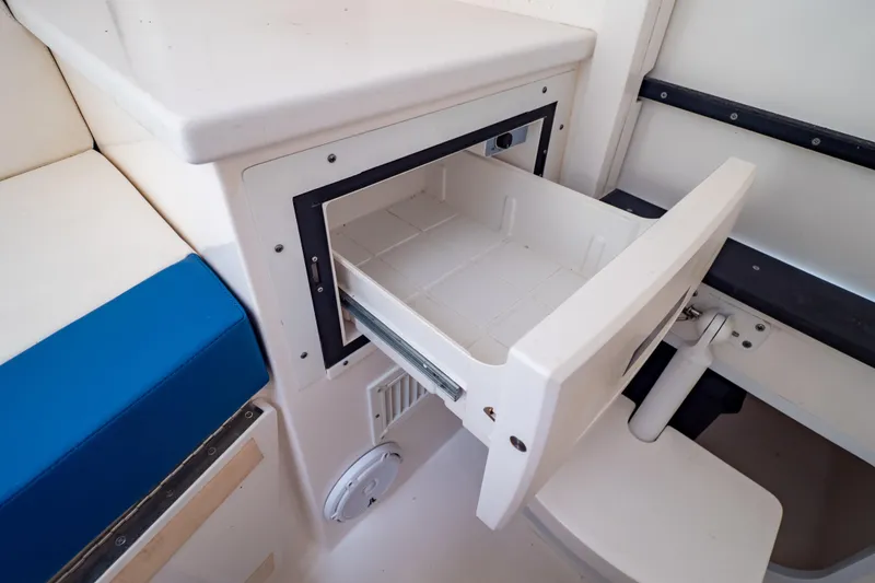 Slide: The Image of Open storage compartment on 2015 Intrepid 327 Cuddy boat, featuring white and blue seating. - 82