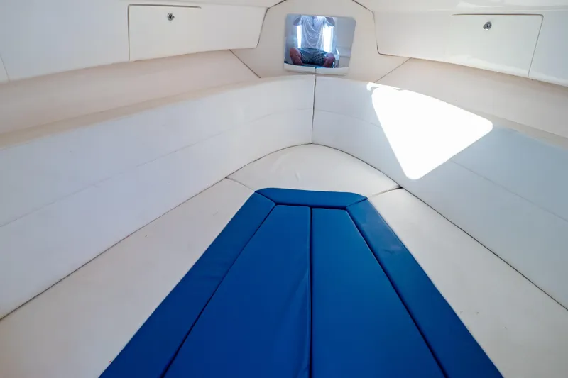 Slide: The Image of 2015 Intrepid 327 Cuddy interior with blue cushions and storage compartments. - 84