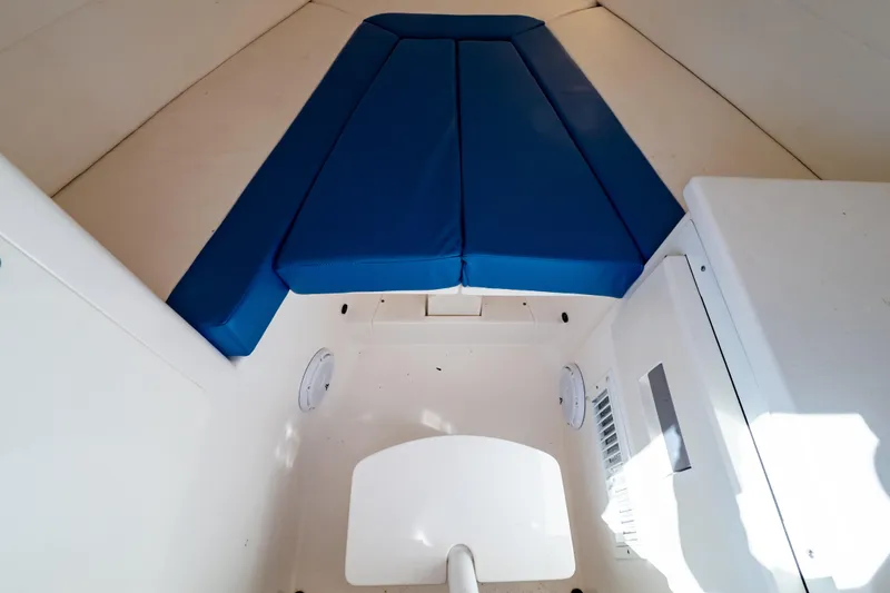 Slide: The Image of 2015 Intrepid 327 Cuddy interior with blue cushions and white cabin features. - 85