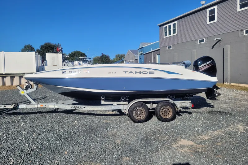 The Image of 2017 Tahoe 2150 boat on trailer, parked outdoors, with Mercury outboard motor. - 0