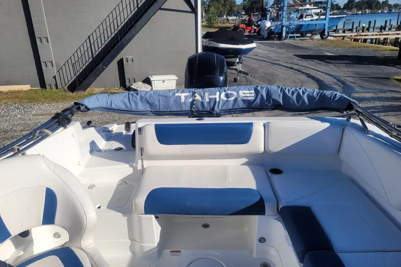 Slide: The Image of 2017 Tahoe 2150 boat interior with blue and white seating, docked near a marina. - 10