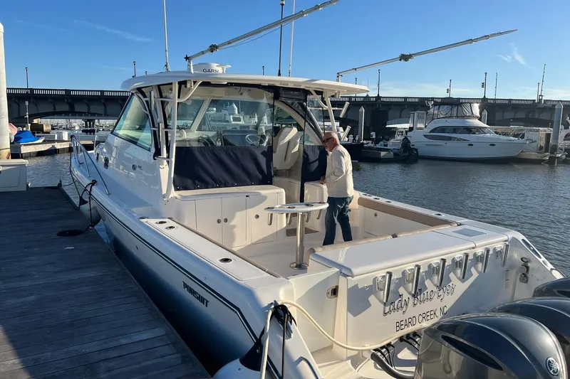 The Image of 2015 Pursuit OS 385 Offshore boat on stands, displayed outdoors under clear blue sky. - 0