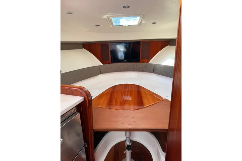 Slide: The Image of 2015 Pursuit OS 385 Offshore cabin interior with wood table and seating area. - 12