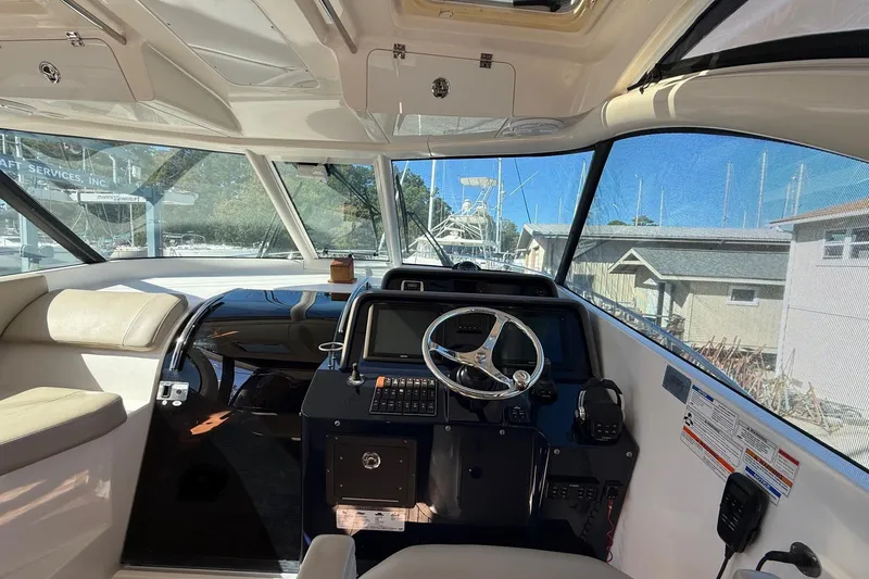 Slide: The Image of 2015 Pursuit OS 385 Offshore boat interior with steering wheel and navigation controls. - 7
