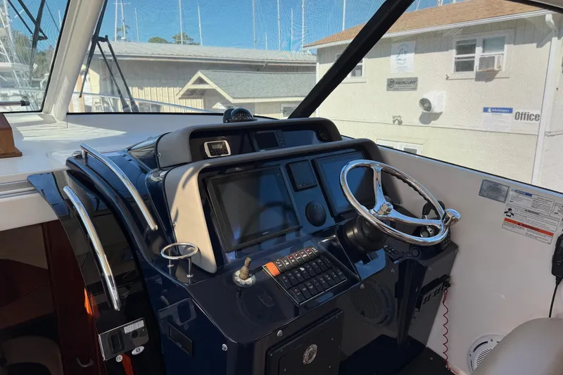 Slide: The Image of Helm of 2015 Pursuit OS 385 Offshore boat with steering wheel and navigation controls. - 8
