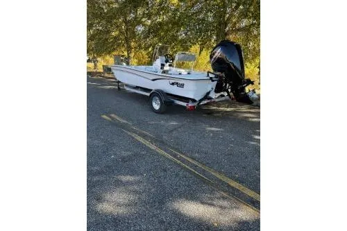 Slide: The Image of 2026 Mako Pro Skiff 17 CC boat on trailer, parked under trees. - 2