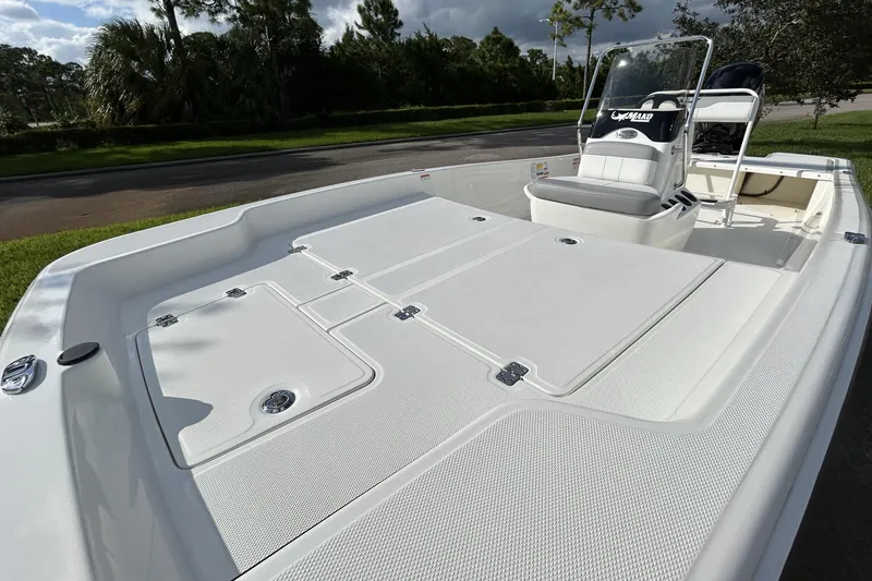 Slide: The Image of 2026 Mako Pro Skiff 17 CC boat with spacious deck and seating, surrounded by lush greenery. - 9