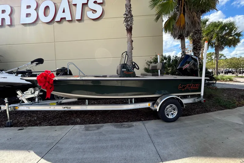The Image of 2026 Mako 18 Pro Skiff Backwater Edition boat on trailer with red bow, outdoor display. - 0