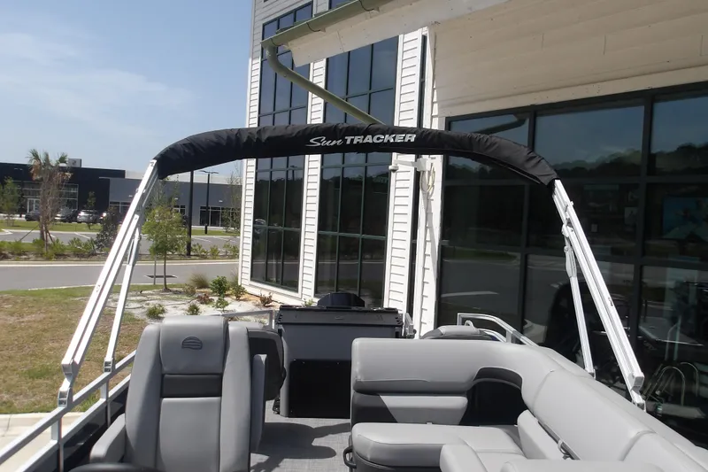 Slide: The Image of 2026 Sun Tracker SportFish 22 XP3 pontoon boat with seating, parked near a modern building. - 52