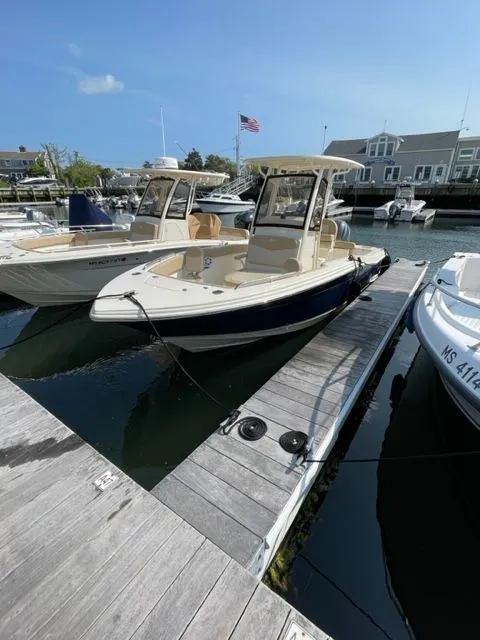 Slide: The Image of 2023 Scout 215 XSF boat docked at a marina under clear blue skies. - 2