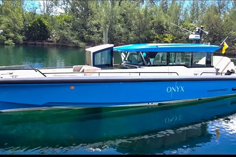 The Image of 2024 Axopar 37XC CROSS CABIN boat in blue, docked on a serene waterway. - 0