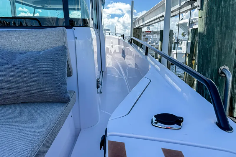 Slide: The Image of 2024 Axopar 37XC CROSS CABIN boat deck with seating, docked under a blue sky. - 10