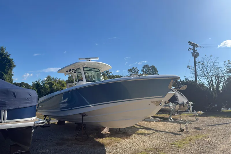 The Image of 2016 Boston Whaler 330 Outrage boat on trailer under clear blue sky. - 0
