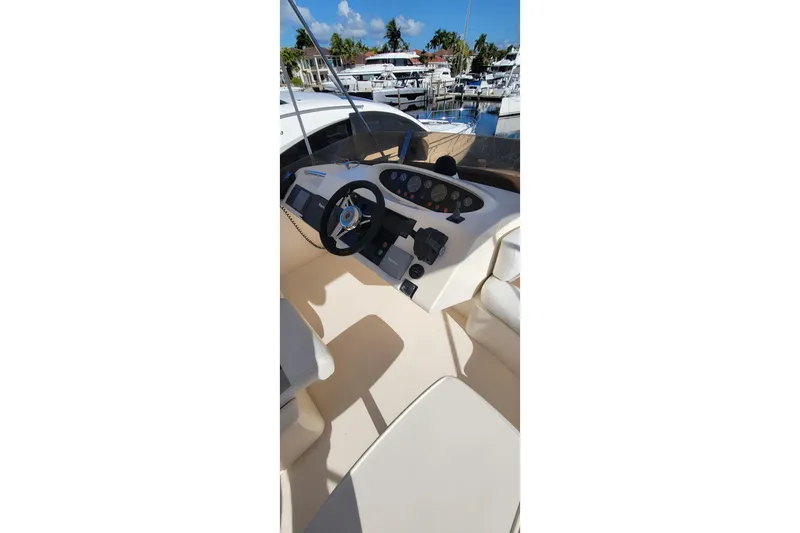 Slide: The Image of 1998 Viking Princess 50 Sport Cruiser interior with white and brown seating, docked among other boats. - 16