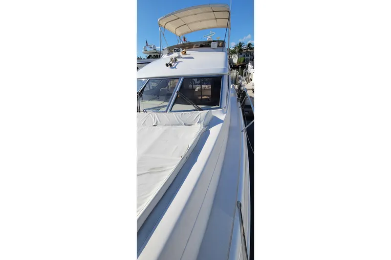 Slide: The Image of 1998 Viking Princess 50 Sport Cruiser with teak deck and cushioned seating at a marina. - 5