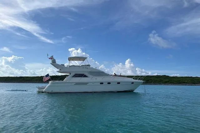Slide: The Image of 1998 Viking Princess 50 Sport Cruiser navigating serene waters under clear blue skies. - 55
