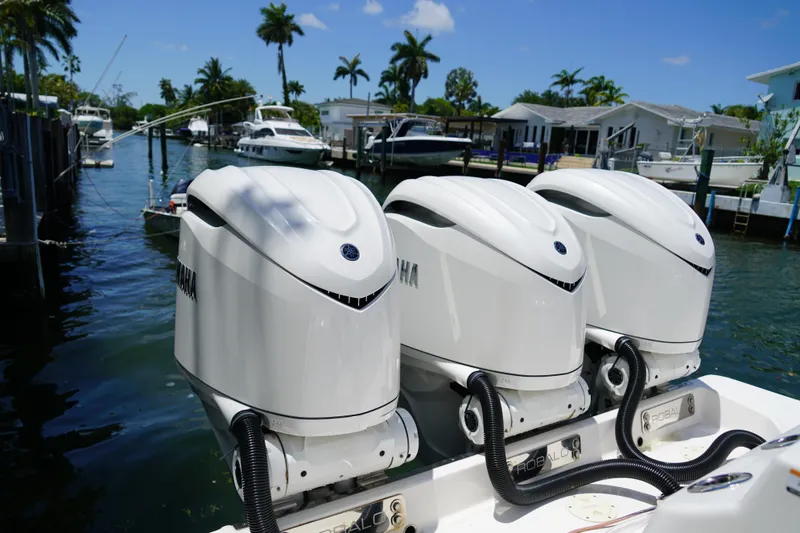Slide: The Image of 2024 Robalo R360 Center Console with triple Yamaha outboard engines docked by waterfront homes. - 18