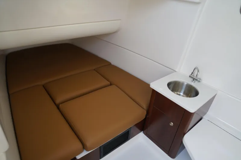 Slide: The Image of 2024 Robalo R360 Center Console cabin with brown cushions and compact sink. - 20