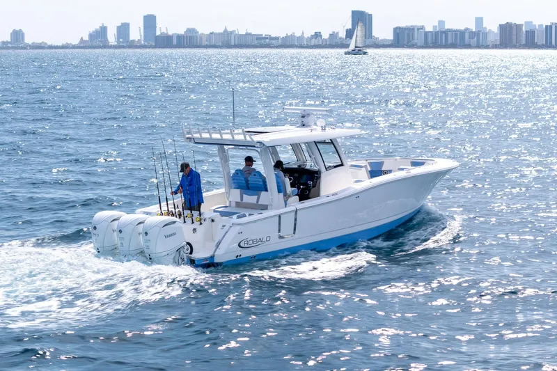 Slide: The Image of 2024 Robalo R360 Center Console boat cruising on sparkling ocean near city skyline. - 3