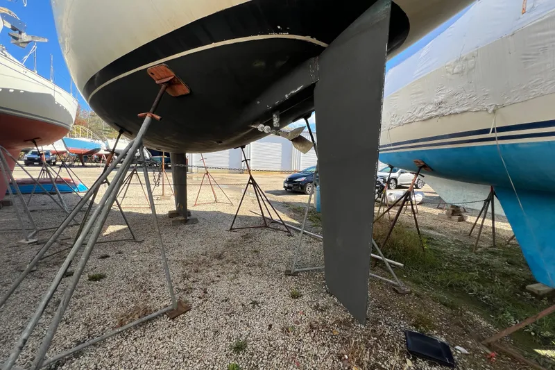 Slide: The Image of Beneteau First 38.5 sailboat from 1983 on stands, showing keel and hull. - 8